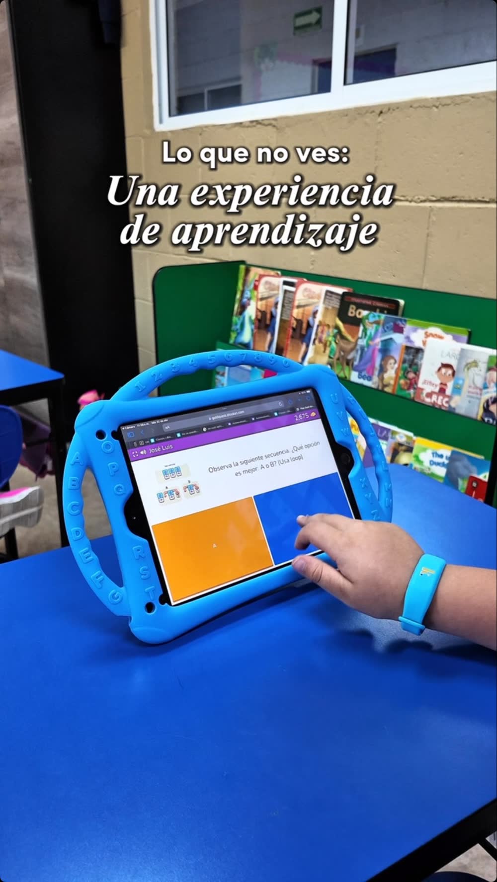 Mano de un estudiante trabajando en una tableta junto a la biblioteca del aula en Keystone Institute